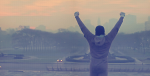 Rocky Balboa comemorando após subir uma longa escadaria.